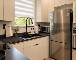 A modern kitchen with a stainless steel refrigerator, a microwave, and a sink with a faucet.