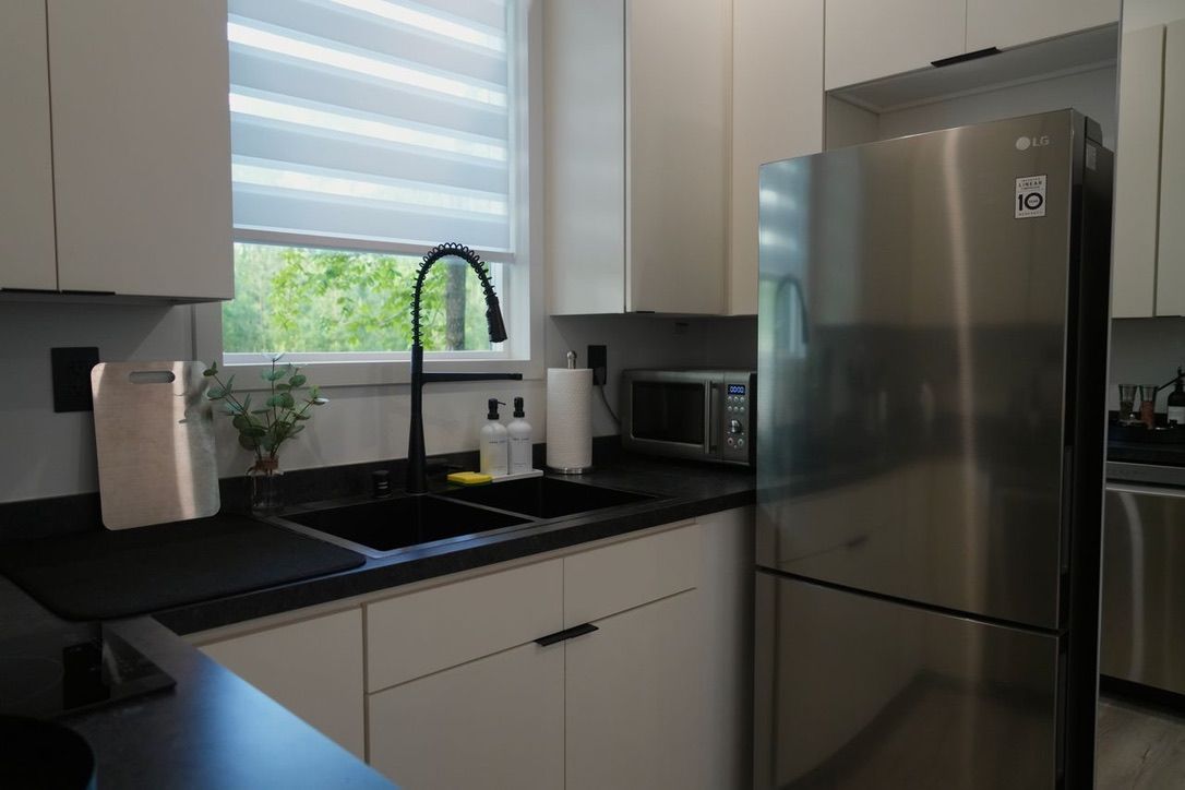 A modern kitchen with a stainless steel refrigerator, a microwave, and a sink with a faucet.