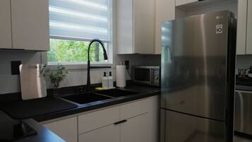 A modern kitchen with a stainless steel refrigerator, a microwave, and a sink with a faucet.