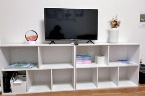 A white entertainment unit with a flat-screen TV, shelves, and a decorative globe. - Hakushin no sha (Osaka)