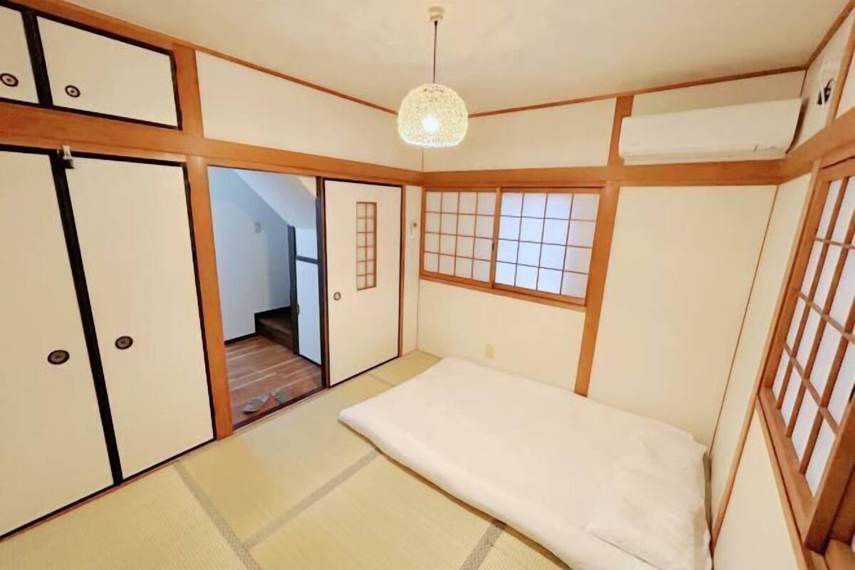 Una tradizionale stanza giapponese con pavimento in tatami, porte scorrevoli e una lampada a sospensione.