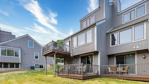 Et moderne hus i to etager med balkon, store vinduer og en velplejet græsplæne.