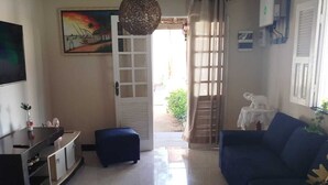 Un saló amb un sofà, una televisió, un armari i una porta que dona a un balcó.