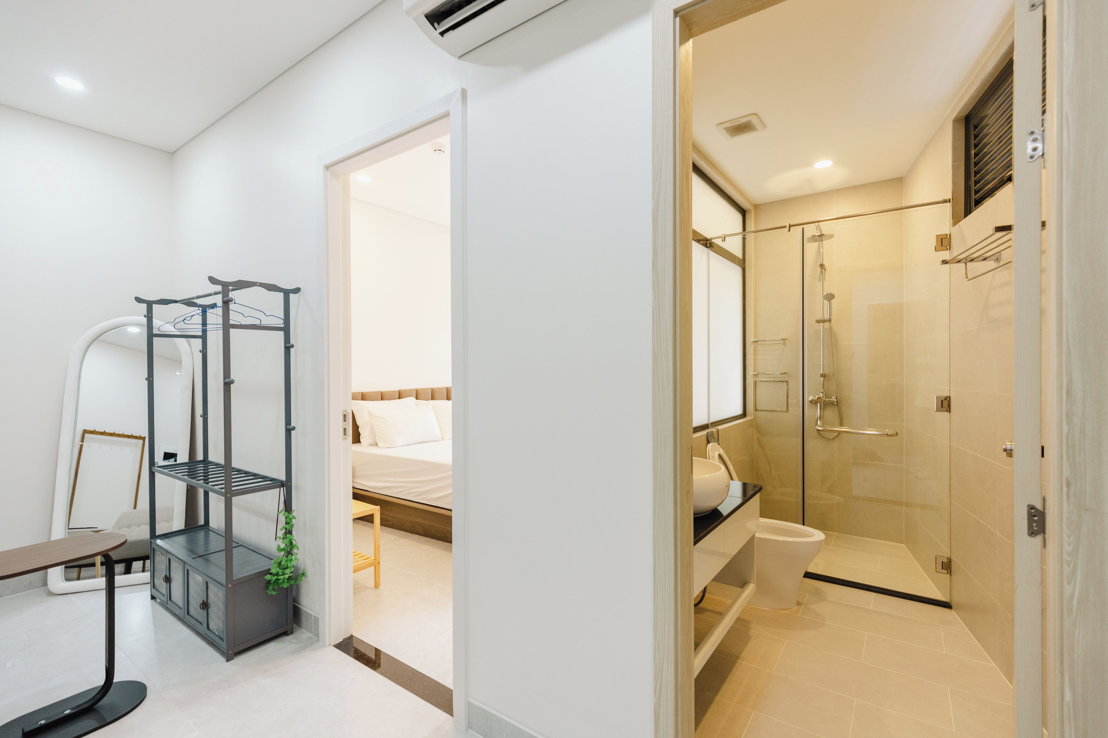 Una camera d'hotel moderna con un letto, un bagno dotato di doccia e un piccolo angolo scrivania.