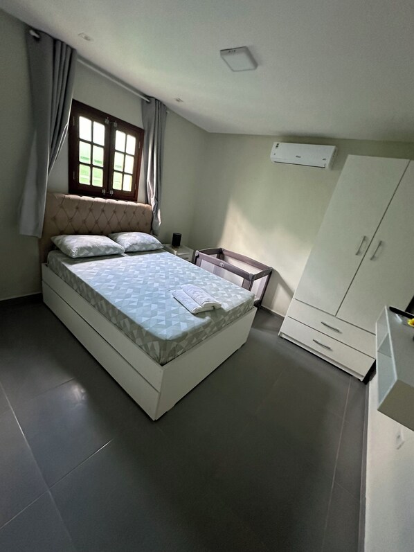 A bedroom with a bed, a wardrobe, a window, and an air conditioning unit. - Portal Araticum Smart Flats (Bonito)