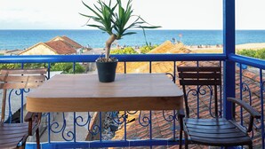 Ein Balkon mit Tisch und Stühlen, einem Blumentopf und Blick auf Strand und Meer.