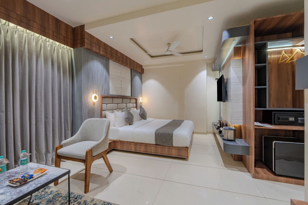 A modern hotel room with a bed, a chair, a desk, and a TV.