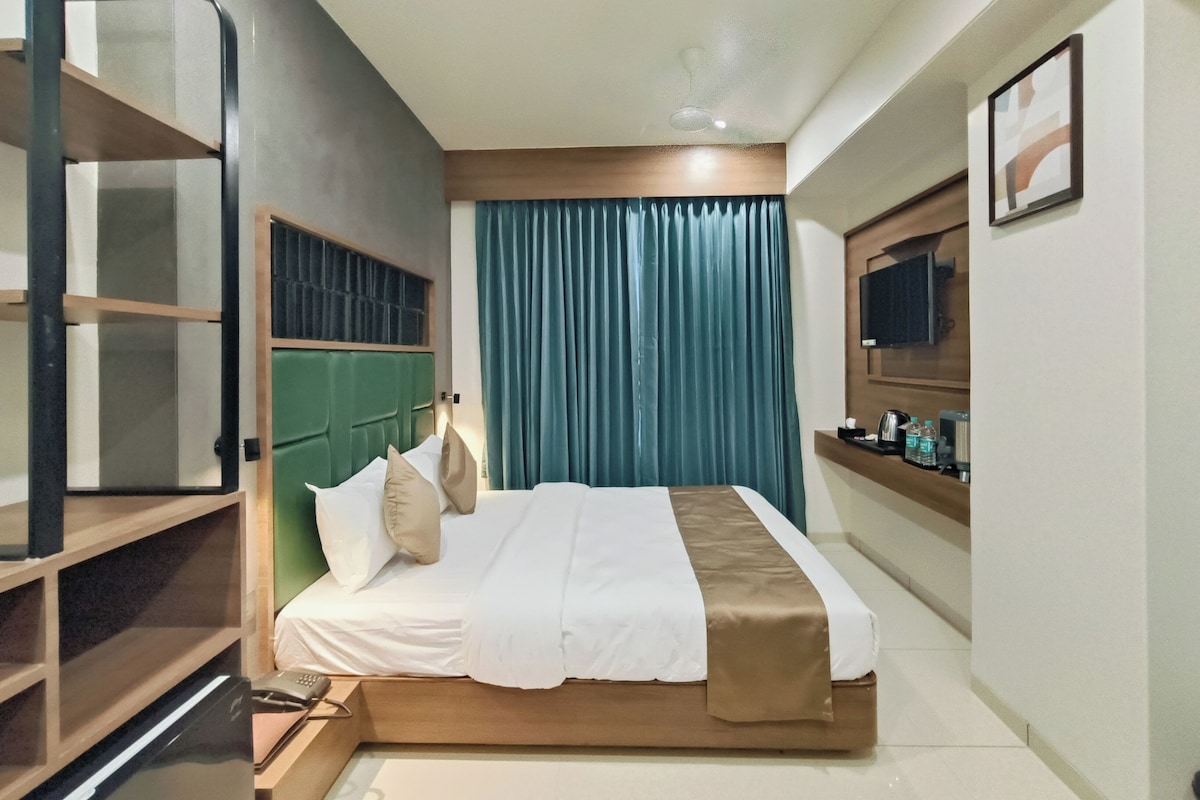 A hotel room with a bed, a desk, a chair, a television, and a window with curtains.