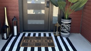 A front door with a frosted glass panel, a black and white striped doormat, a potted plant, and a decorative lantern. - Superb 5-bedroom house with AC in charming Stevensville (Stevensville)