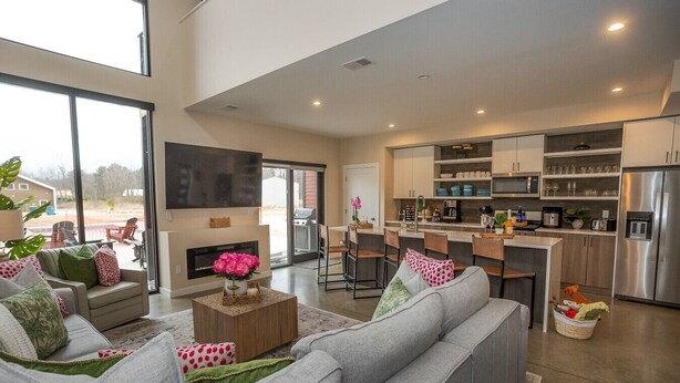 A modern living room with a fireplace, grey sofas, and a coffee table. - Superb 5-bedroom house with AC in charming Stevensville (Stevensville)