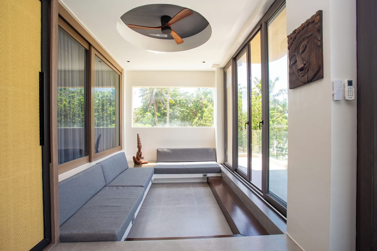 A modern interior with a built-in bench, large windows, and a ceiling fan.