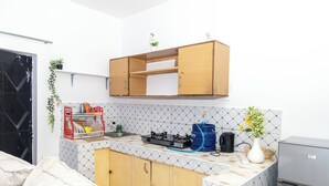 A compact kitchen with a wooden cabinet, a gas stove, and a coffee maker. - Grace's cozy one bedroom Kilifi apartment (Kilifi)