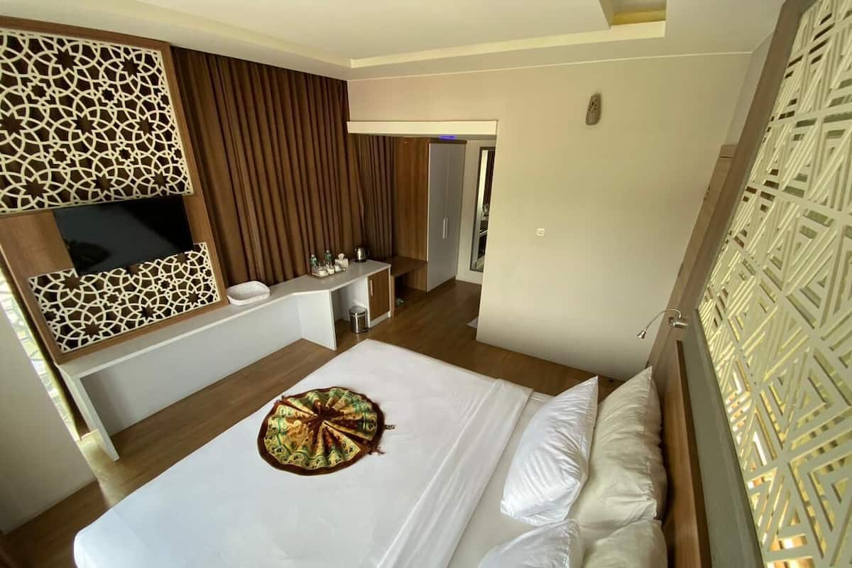 Une chambre d’hôtel avec un grand lit, un bureau, un miroir et une armoire.