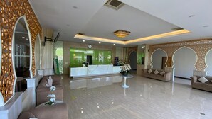 A hotel lobby with a reception desk, sofas, and a decorative wall. - Grand Bunda Hotel Syariah Bukittinggi Powered By Archipelago (Bukittinggi)