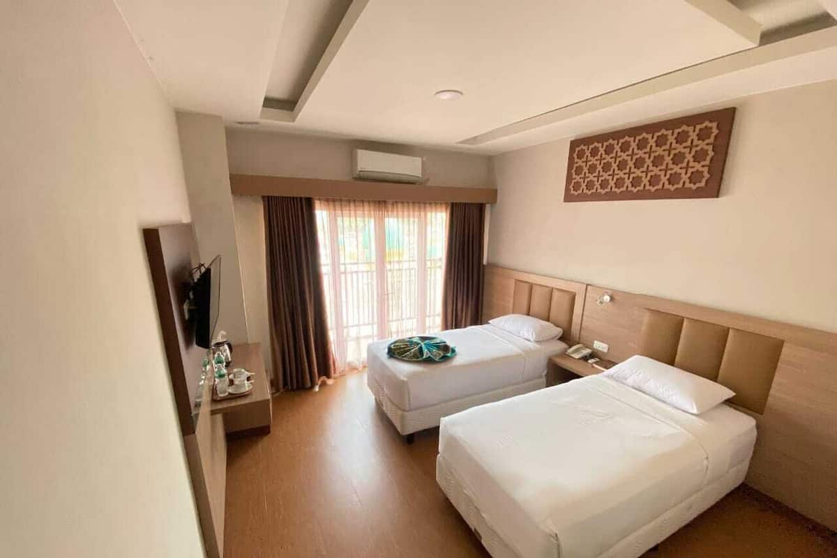 Une chambre d’hôtel avec deux lits, une télévision et une fenêtre avec des rideaux.