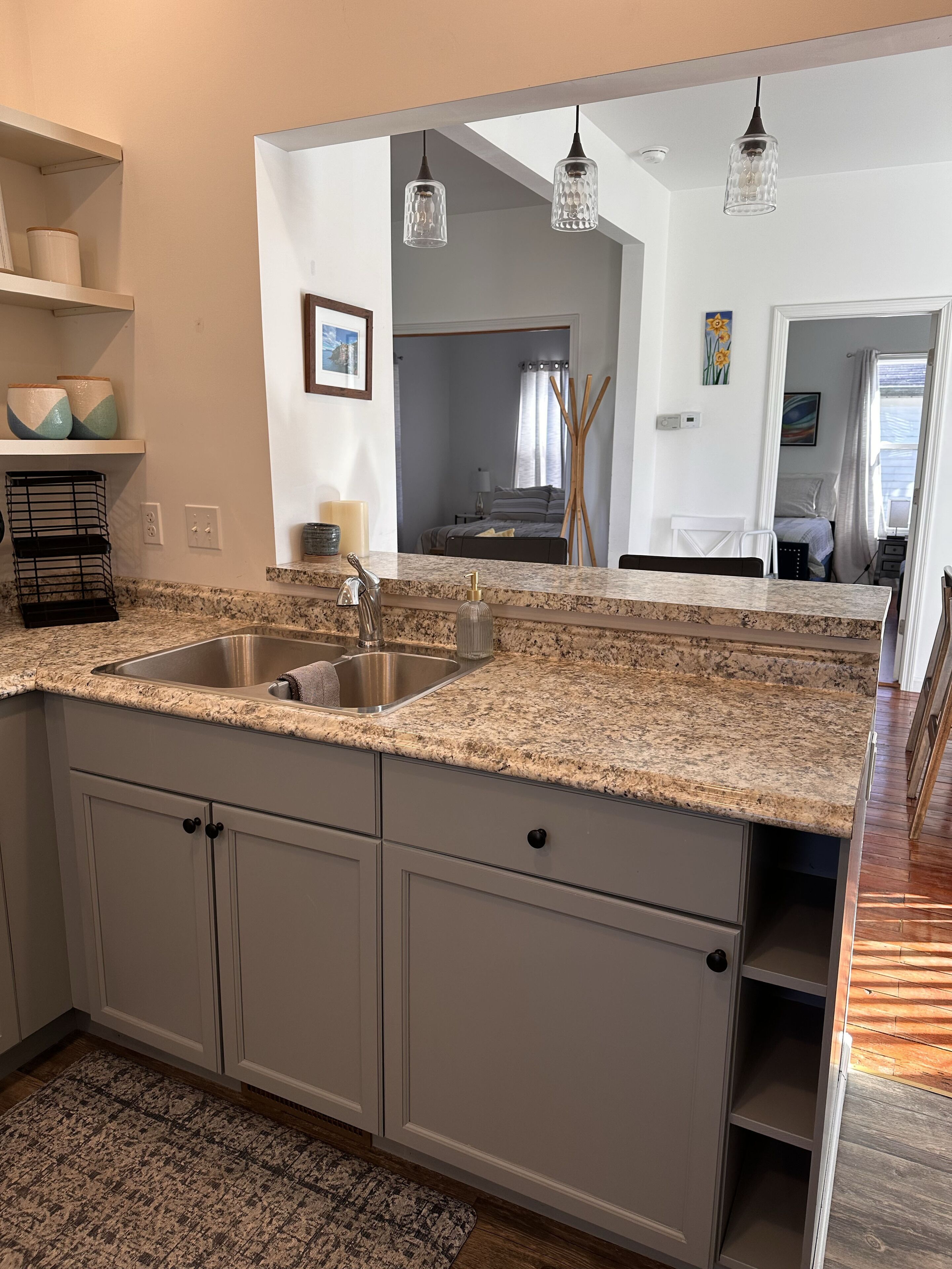A kitchen with granite countertops, a double sink, and grey cabinets.