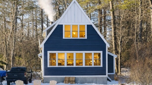 Eine Hütte mit einer großen Veranda, umgeben von Schnee.