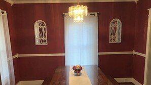 Un comedor con una amplia mesa de madera, mantel blanco y una lámpara de araña.