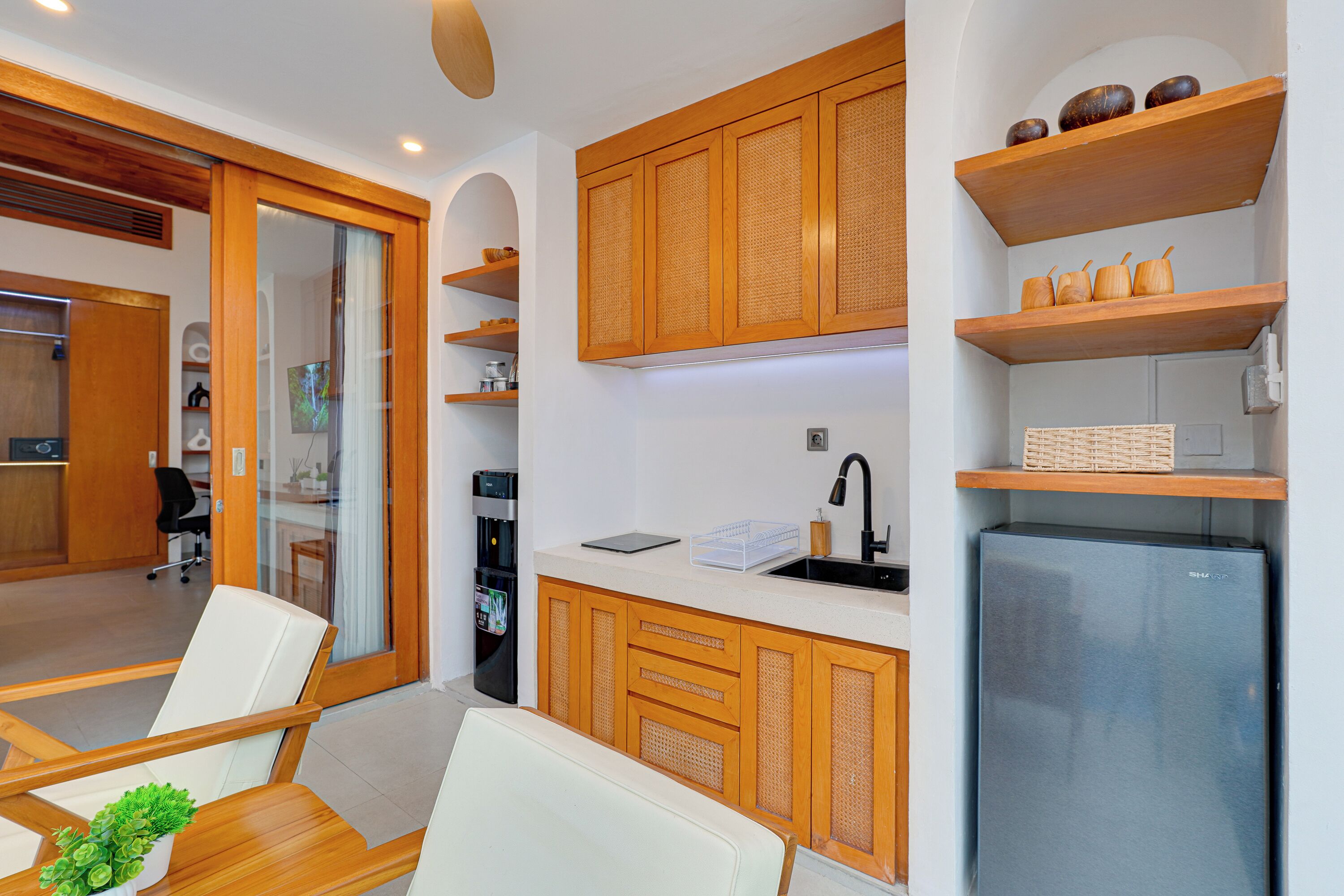 Una cocina moderna con armarios de madera, un refrigerador integrado y un comedor con mesa y sillas blancas.