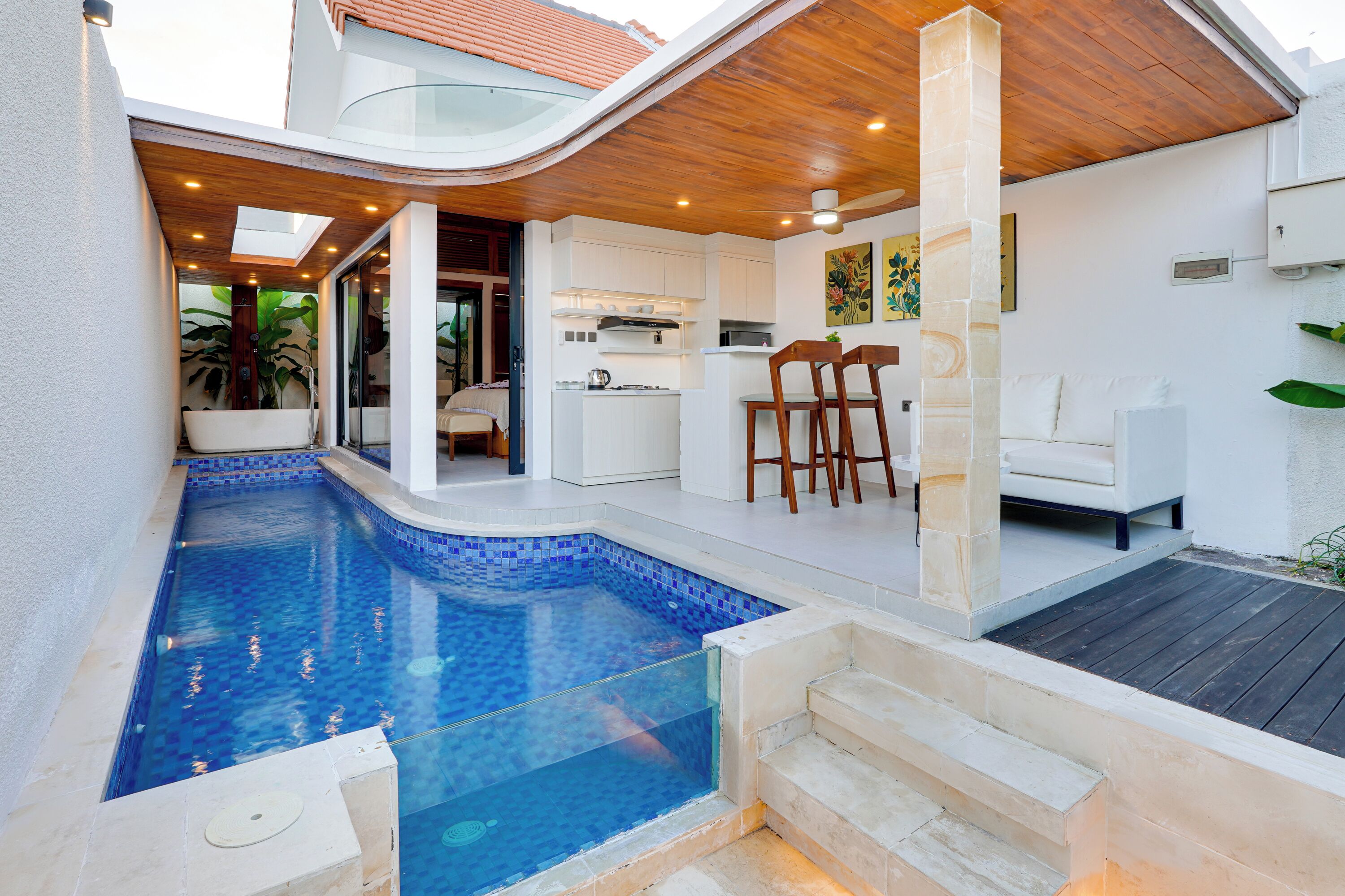 A modern outdoor pool area with a kitchen and seating area.