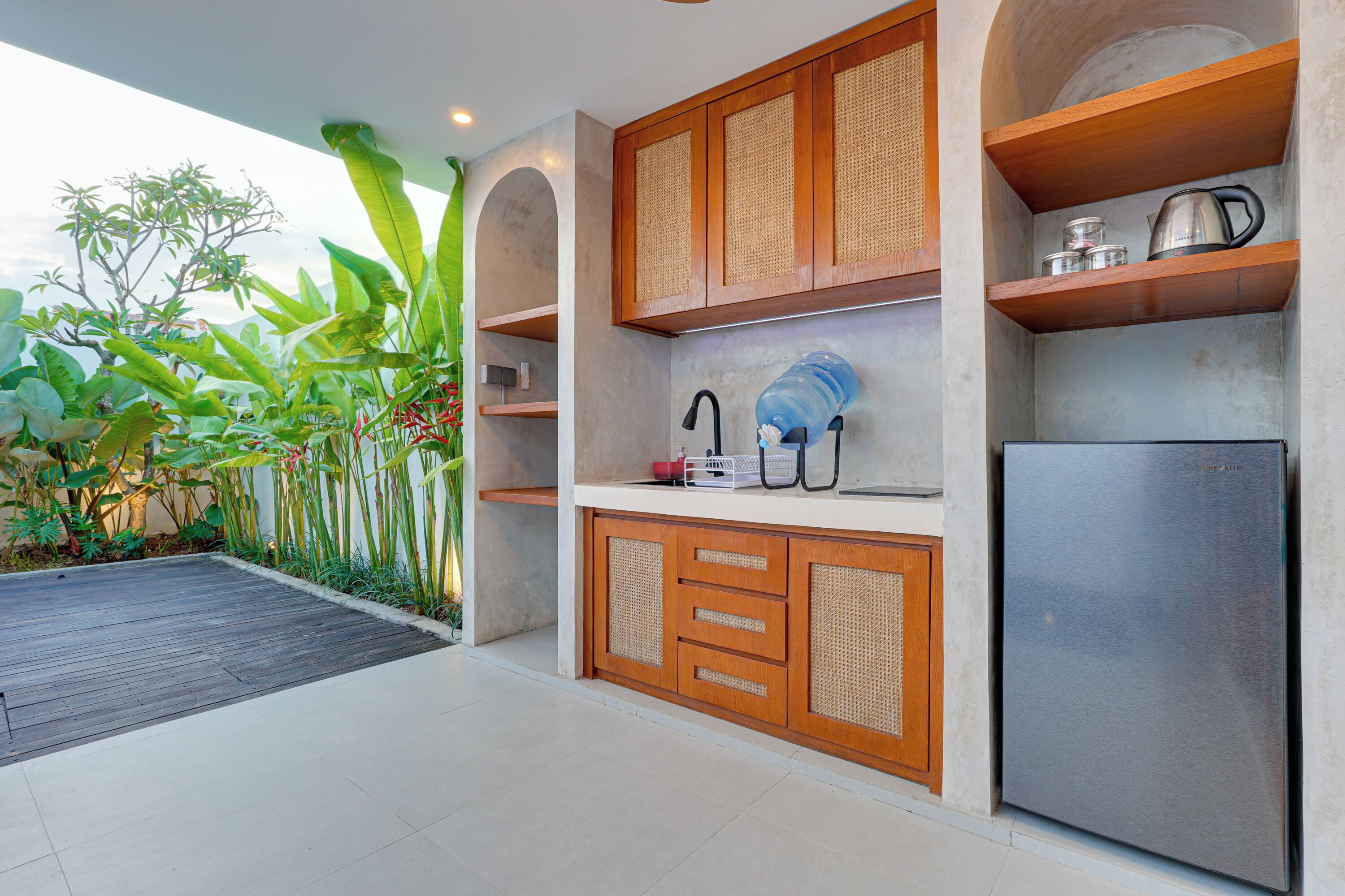 A modern kitchen with wooden cabinets, a stainless steel refrigerator, and a water dispenser.