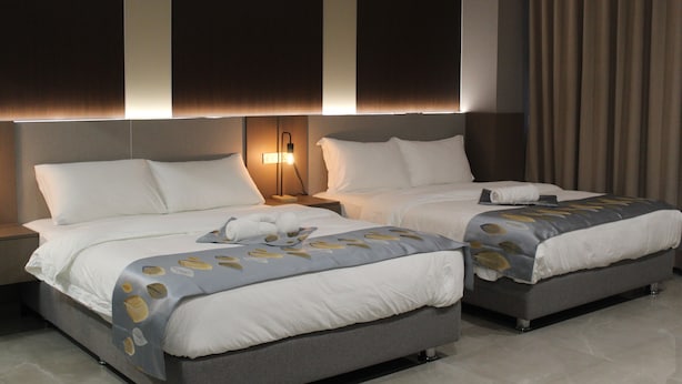 A hotel room with two beds, a nightstand, a lamp, and a view of the city skyline. - Twin Sky Suite – Spacious, Stylish, Serene (Parañaque)