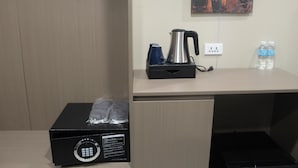 A hotel room with a wooden desk, a kettle, two water bottles, and a box with a lock. - King Sky Suite – Spacious. Stylish (Parañaque)