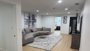 Ein modernes Wohnzimmer mit einer Eckcouch, einem Couchtisch und einem großen, abstrakten Gemälde an der Wand.