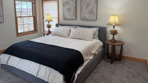 Ein Schlafzimmer mit einem Bett, zwei Nachttischlampen, einem Deckenventilator und Kunstwerken an der Wand.