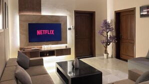 Una sala de estar moderna con un televisor de pantalla plana grande montado en la pared, una mesa de centro negra y un juego de sofás.