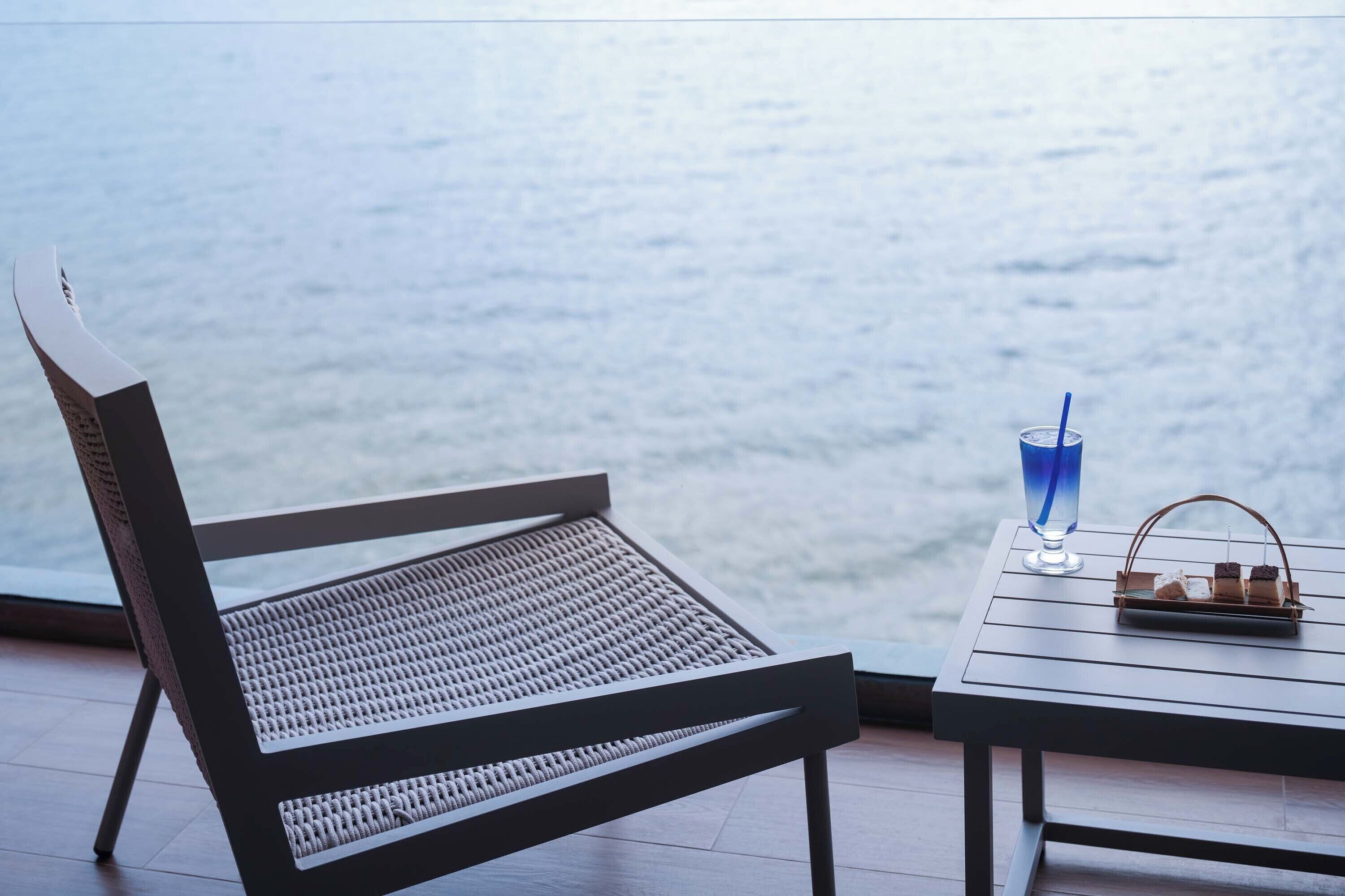 A chair and table with a view of the sea.