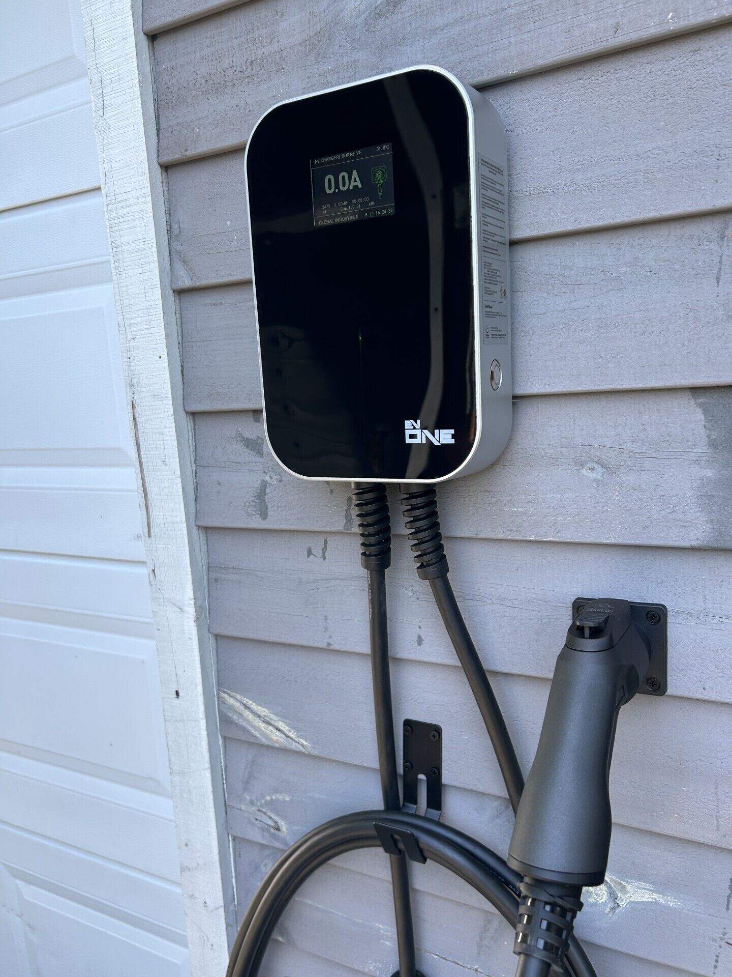 An electric vehicle charging station mounted on a house wall.