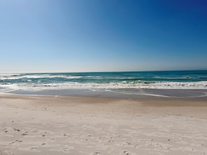 Une plage où l’on voit des empreintes dans le sable et où les vagues se rapprochent du rivage.