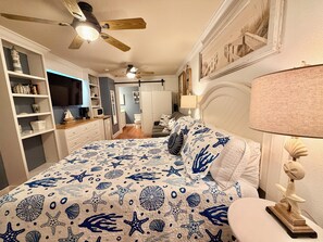A bedroom with a bed, a nightstand, a lamp, and a ceiling fan.