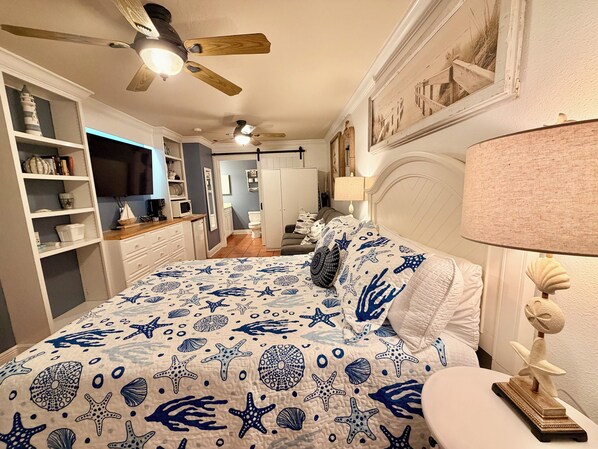 Une chambre à coucher avec un lit, une table de chevet, une lampe et un ventilateur de plafond.