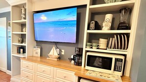 Ett kök med inbyggd TV, mikrovågsugn och kylskåp.