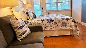 Ett sovrum med en säng, en soffa, en lampa och ett fönster med persienner.