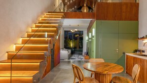 A modern interior with a wooden staircase, a dining area, and a kitchen. - Adva Garden Village (Canggu)