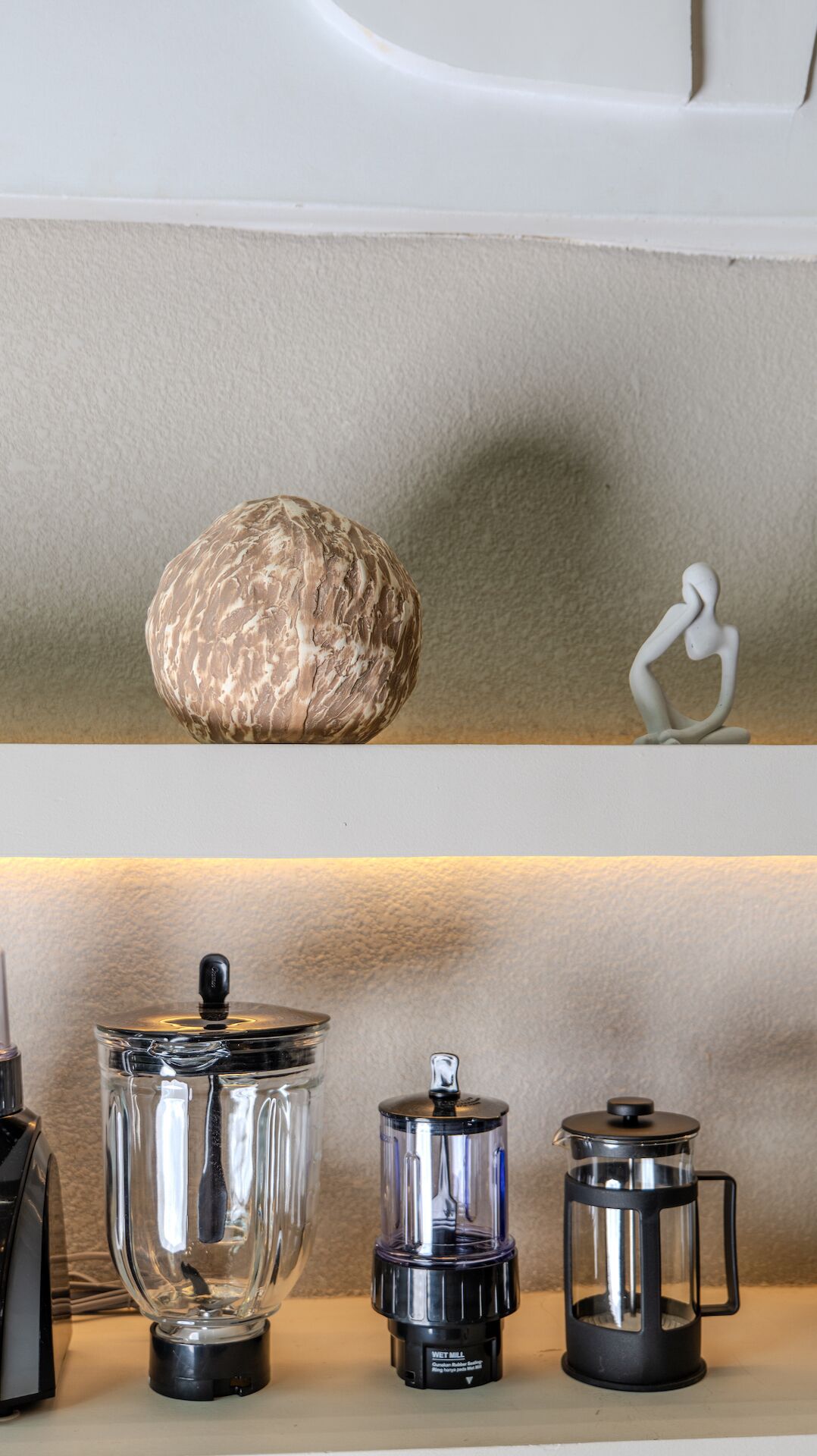 A kitchen counter with a coffee maker, a grinder, and a French press.