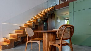 Un escalier moderne avec des marches en bois et un éclairage intégré, menant à un coin repas comprenant deux chaises en bois et une table.