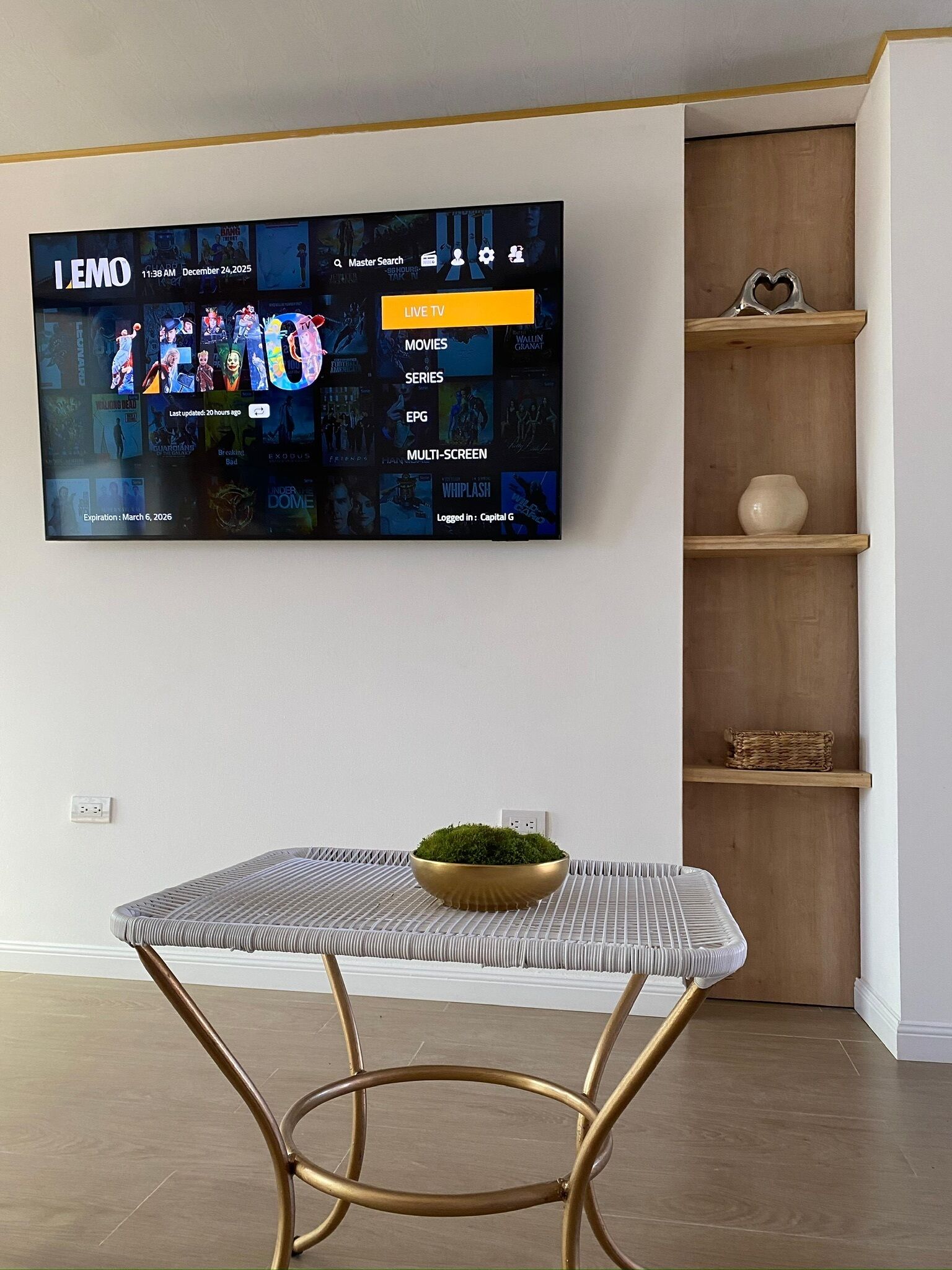 A flat-screen TV mounted on a wall displaying a streaming service interface with various content categories.