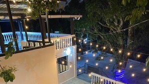 Un espace extérieur aménagé pour la nuit, avec une fontaine, des marches et des guirlandes lumineuses.