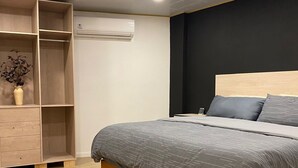 Une chambre à coucher comprenant un lit, une armoire et un appareil de climatisation.