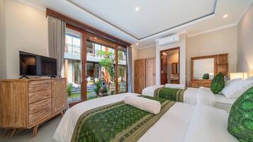 Quarto de hotel com duas camas, televisão, cômoda de madeira e vista para o exterior.