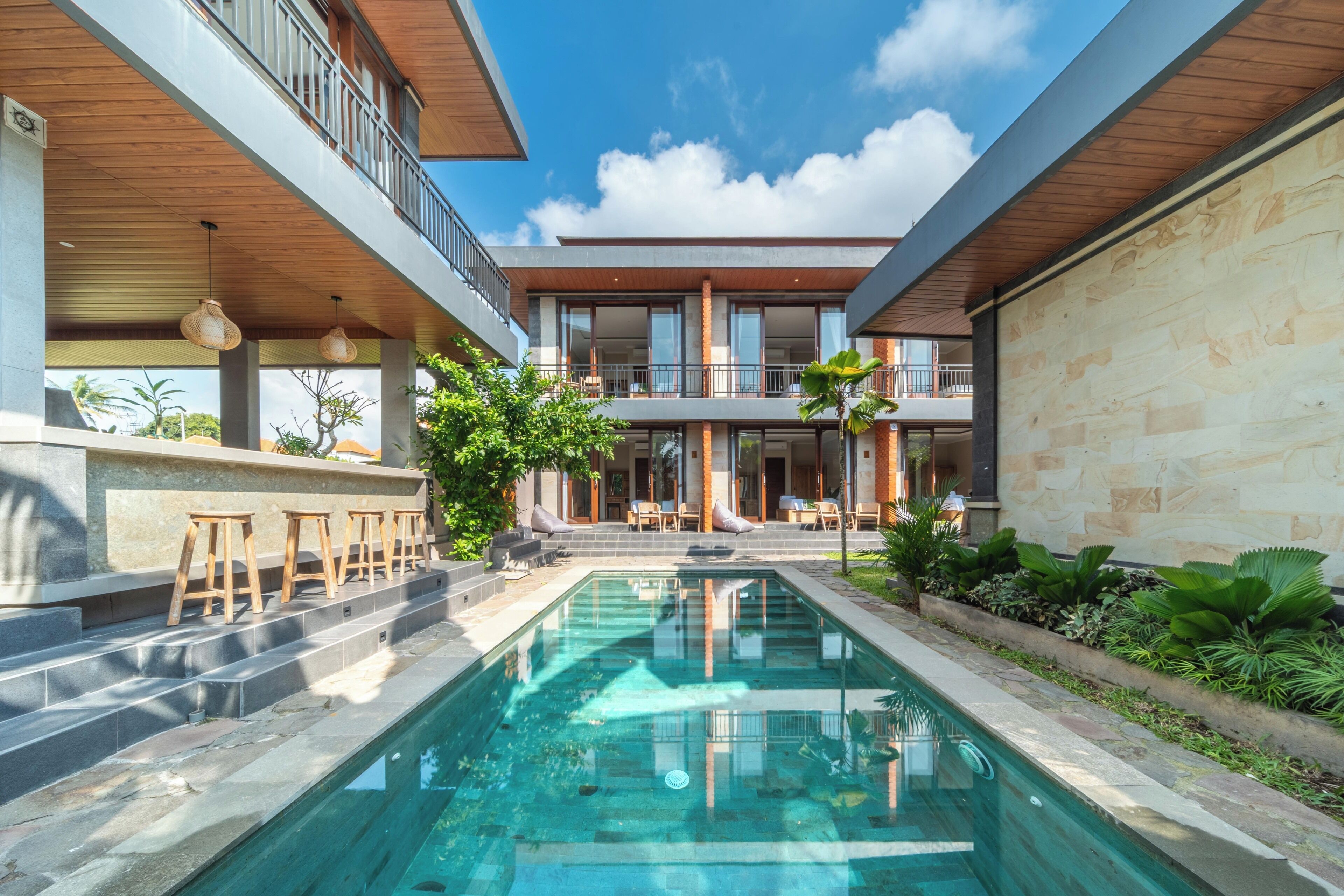 Un edificio moderno con piscina, mobiliario exterior y una estructura de dos pisos.