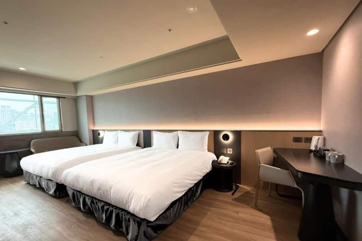A modern hotel room with a large bed, bedside tables, a desk, and a chair.