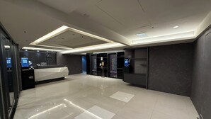 Un moderno vestíbulo de hotel con una recepción, quioscos de información digital y un piso de baldosas limpias.