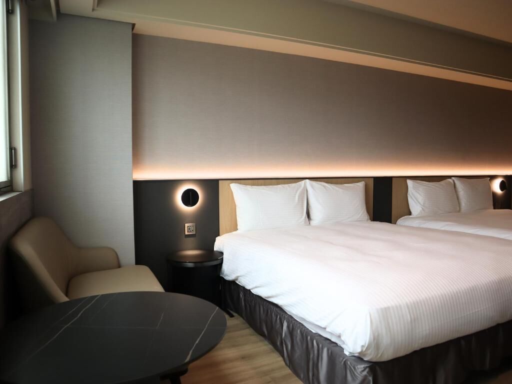 Une chambre d’hôtel moderne avec un grand lit, une table de chevet, une chaise et un bureau.