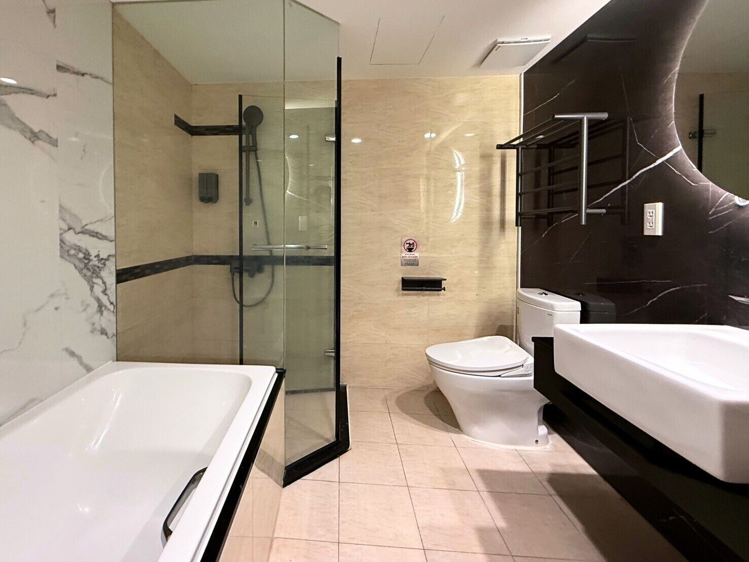 A modern bathroom with a glass-enclosed shower, a toilet, and a bathtub.