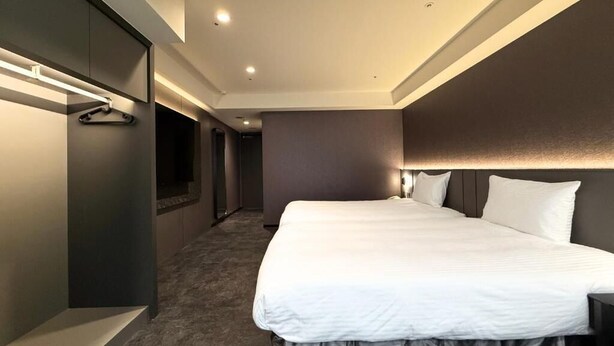 Una habitación de hotel moderna con una cama grande, un vestidor amplio y un pasillo que conduce a otras habitaciones.